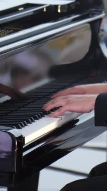 Yetenekli bir piyanist, açık havada muazzam bir yetenek sergileyerek büyük bir piyanoda performans sergiliyor. Kırp