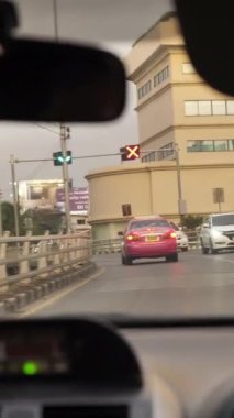 Video, yoğun trafikte yol alan, açık bir otoyola geçiş yapan, arabanın içinden perspektifler sunan hareketli bir şehir tasvir ediyor.