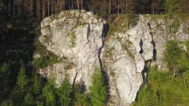Canlı ağaçlar ve çevreleyen doğal güzelliklerle çerçevelenmiş dingin bir su kütlesi tarafından çarpıcı bir kaya oluşumu. Menkul Kıymetler