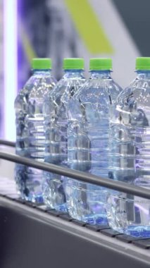 Otomatik üretim bandı su şişelerini bir imalat tesisinde dağıtılmaya hazır hale getiriyor. Medya