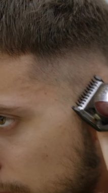 Bir adamın saç kesiminin yakından görüntüsü, kullanılan maharetli ve hassas kesme tekniğini vurguluyor.