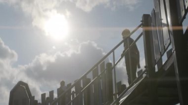 Genç bir çocuk neşeyle canlı bir oyun parkından kayıyor, sıcak güneş ışığında parlıyor, mutluluğu somutlaştırıyor. Eylem