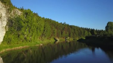 Sakin ve sakin bir nehir canlı yeşil yaprakları ve engebeli kayalık uçurumları yansıtarak mükemmel bir ahenk yaratır. Menkul Kıymetler