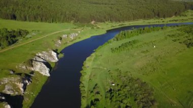 Canlı yeşil tepeler ve sarp kayalıklarla çevrili dolambaçlı bir nehrin nefes kesici hava manzarası. Menkul Kıymetler