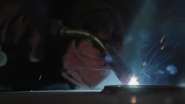 Yetenekli bir kaynakçı karmaşık metal işleriyle uğraşır. Endüstriyel bir ortamda parlak kıvılcımlar ve kalın dumanlar yaratır. Menkul Kıymetler