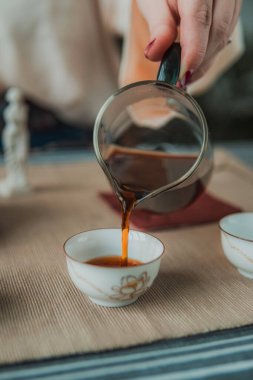 Nazik bir el, güzel kokulu, aromatik çayı huzurlu ve davetkar bir ortam içinde güzel bir fincana doldurur.