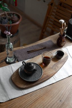 Bir çaydanlık, narin bir çay ve ahşap bir masanın üzerindeki zarif bir dekorla serinletici bir atmosfer yaratır.