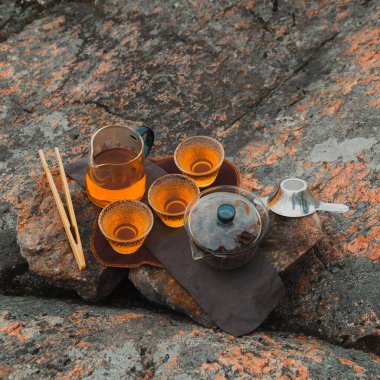 Kayalık bir arka planda fincanlar ve demlikle sakin bir çay, rahatlama ve doğa titreşimleri için mükemmel..