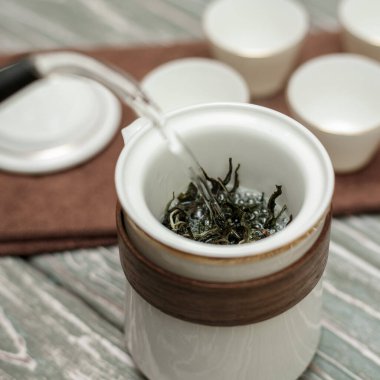 Nefis bir çay demleme sahnesi güzel yeşil çay yapraklarını güzel bir porselen demlikte sergiler.