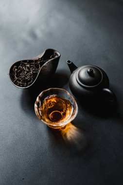 Zarif, sakin bir kompozisyon çay yaprakları, dekoratif bir çaydanlık ve demlenmiş çayla dolu bir bardak.