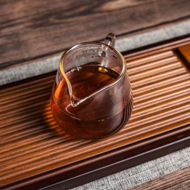 Nefis bir cam çaydanlık, dumanı tüten çaydanlıkla dolu, kırsal ahşap servis tepsisine yerleştirilmiş.