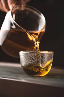 Zarif bir cam fincana çay dökerken, zarafet ve sıcaklığı gösteren huzurlu bir an.