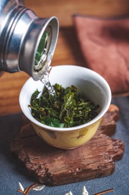 Huzurlu ve rahat bir ortamda, ılık su yavaşça demlenmiş yeşil çay yapraklarının üzerine dökülür.