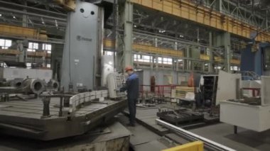 Kendini işine adamış bir işçi, hızlı ve modern imalat ortamında büyük makineler çalıştırır. Menkul Kıymetler