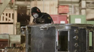 Endüstriyel atölye ortamında, maskeli bir operatör ustalıkla metal öğütme işini hassas aletlerle yapıyor. Menkul Kıymetler