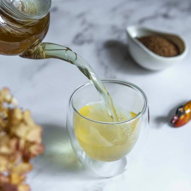Nefis kokulu bitki çayının nefis bir manzarası berrak bir bardağa dökülüyor, aromatik baharatlarla çevrili.