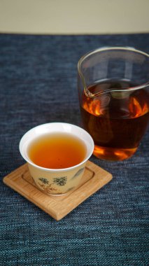 Geleneksel bir fincan ve modern bardakla zarif bir çay sunumu, desenli bir yüzey üzerinde güzelce düzenlenmiş.