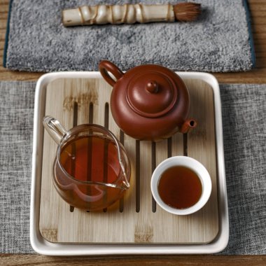 Zarif bir çay seti, güzel bir kil çaydanlık, şık bir cam sürahi ve ahşap tepside sevimli bir fincan.