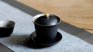 Çağdaş bir masaya konmuş modaya uygun bir siyah çay fincanı seti çay meraklıları ve ev dekorasyonu için ideal.