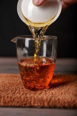 Sıcacık, aromatik bir sıvıyı bardağa ustalıkla dökerek içeceği ön plana çıkaran bir elin güzel yakın plan çekimi.