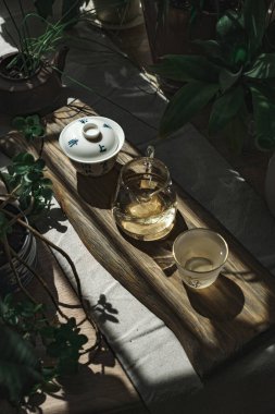 Bereketli yeşillik ve rahatlama ve farkındalık ortasındaki zarif zanaatkar eşyalarla sakin bir çay seti.