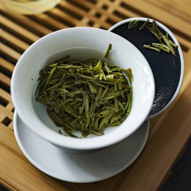 Görsel olarak çarpıcı bir sahnede taze yeşil çay yaprakları dikkatlice dizilmiş güzel ve zarif tebliğ edilir.