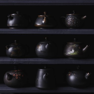 Benzersiz tasarımlar ve olağanüstü bir ustalığa sahip siyah çaydanlıkların zarif bir şekilde sergilenmesi.