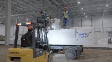 Gürcistan, Tiflis - 7 Kasım 2024: İşçiler yoğun bir inşaat sahasında forklift kullanmakta ve çeşitli maddi hareketler üzerinde işbirliği yapmaktadırlar