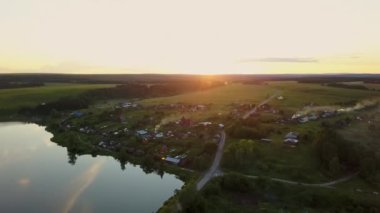 Canlı yeşillik ve doğal güzelliklerle çevrili sakin bir göl kenarındaki sakin bir köyün havadan görünüşü. Menkul Kıymetler