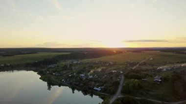 Sakin ve huzurlu bir günbatımı, sakin bir gölün yanındaki güzel kırsal alana nazikçe ışık tutuyor. Menkul Kıymetler