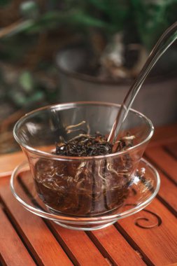 Nefis bir fincan taze demlenmiş bitki çayı, şeffaf cam bir fincanda ustaca demlenmiş, yanında da gümüş bir kaşık.