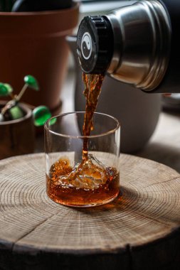 Rahatlatıcı sıcak bir içecek dikkatlice bir bardağa dolduruluyor. Etrafı güzel bir dekorasyonla çevrili.