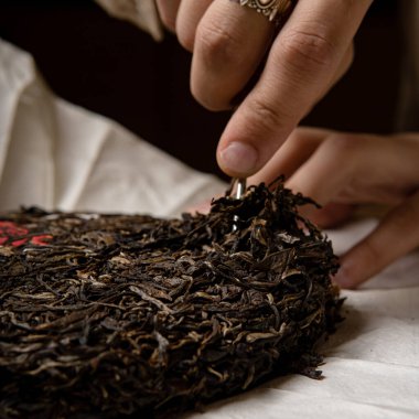 Bir insan zarif bir çay keki hazırlıyor, geleneksel çay sanatını ustalıkla sergiliyor.