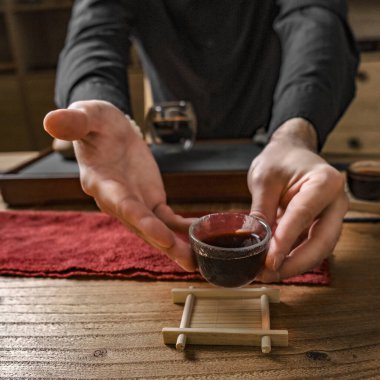 Huzurlu ve sakin bir çay seremonisi zarif bir cam fincanda servis edilen güzel koyu bir içki sergiliyor.