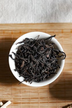 Closeup of dried black tea leaves elegantly arranged in a bowl, perfect for tea lovers and culinary uses clipart