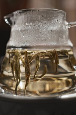 Sıcak suda zarif bir şekilde dönen çay yapraklarının güzel yakın plan görüntüsü çay demleme sanatını gözler önüne seriyor.