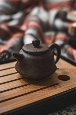 Bambu tepsinin üzerinde dinlenen kırsal bir çaydanlık, rahat bir arka planla çevrili, çay meraklıları için mükemmel..