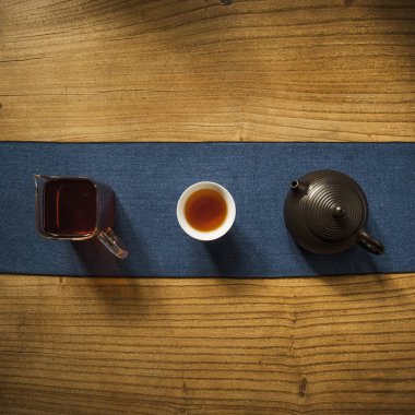 Kırsal bir ahşap masanın üzerinde güzel bir çaydanlık ve fincanın bulunduğu zarif bir çay seti.