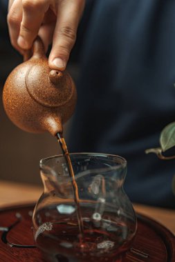 Huzurlu bir an güzel bir çay sanatını yakalıyor kilden bir çaydanlıktan güzel bir cam kaba dökülüyor.
