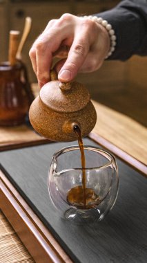 Bir zanaatkar güzel işlenmiş cam bir fincana güzel kokulu çay döker, zarif demleme teknikleri sergiler.