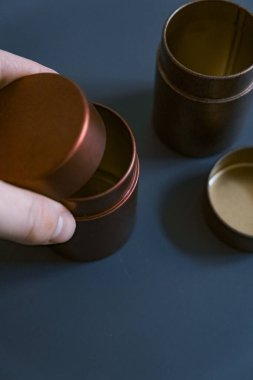 Zarif bir şekilde zarif bir arka planda güzelce yerleştirilmiş metal konteynırları tutan bir el.