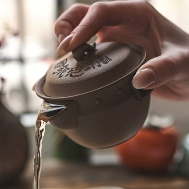 Geleneksel bir çaydanlıktan ustalıkla kokulu çay dökülen bir elin büyüleyici yakın çekimi.