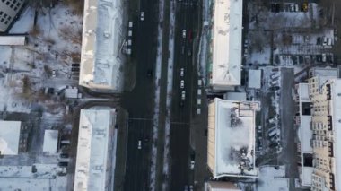 Karlı bir şehir manzarasını ve hareketli hayatla dolu bir sokak trafiğini gösteren güzel bir tepeden çekim. Kırp