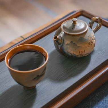 Büyüleyici bir ahşap tepsiye konmuş bir çaydanlık ve fincan arkadaşlarla çay içmek için sakin bir ortam yaratıyor.