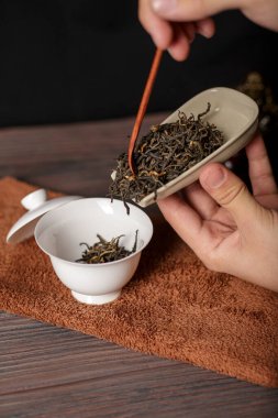 Nazikçe yetenekli bir el gevşek, mis kokulu çay yapraklarını demleme işlemi için nefis bir seramik kaba döküyor.
