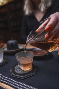 Huzurlu bir çay demleme anı görüntülenir, hassas cam süslemeler ve sıcak, davetkar ışıklar sergilenir.