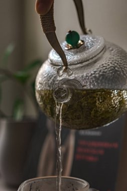 Güzelce hazırlanmış ve zarif bir çaydanlık aromatik bitki çayı döker, sükuneti ve sıcaklığı gösterir.