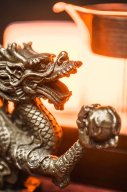 Güç ve bilgeliği temsil eden gümüş bir ejderha heykeli sıcak bir arkaplanda duruyor.