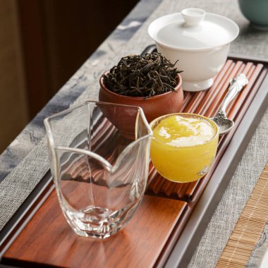 Zarif cam kaplamalı güzel sakin bir çay seti zengin yeşil çay yapraklarıyla birlikte.