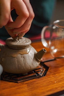 Dikkatli bir el, çay seremonisinin rahatlatıcı deneyimini artırmak için hassas bir çaydanlığa kapak koyar.